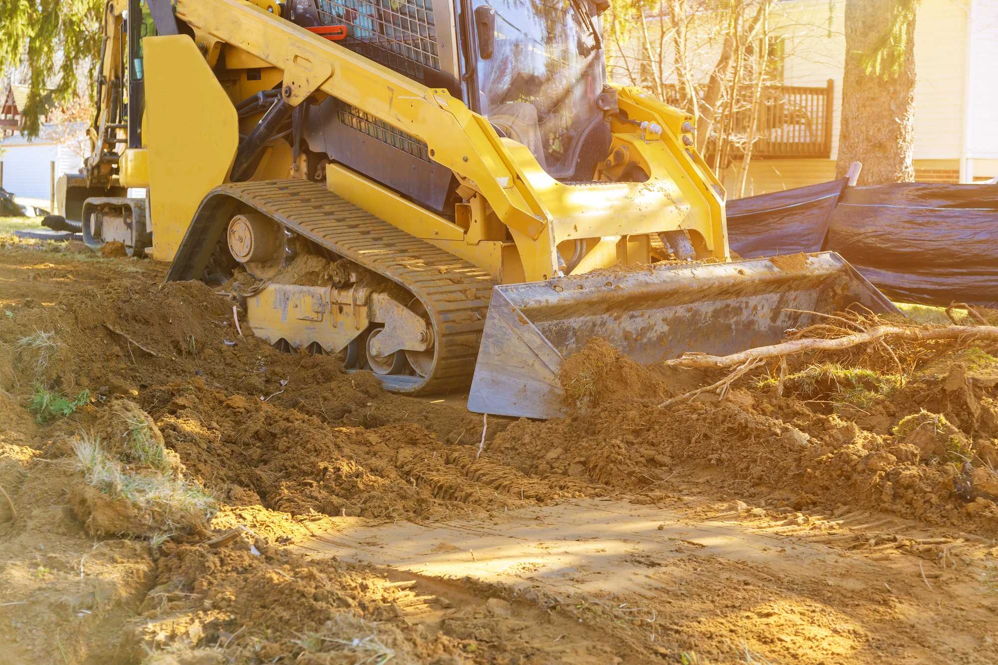Mini bulldozer working with earth while doing landscaping works on construction moving soil